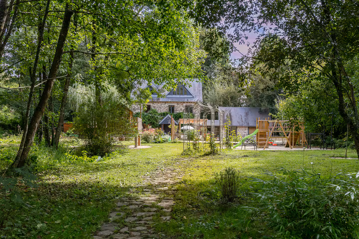 Woodland path across the lawn towards the stone house
