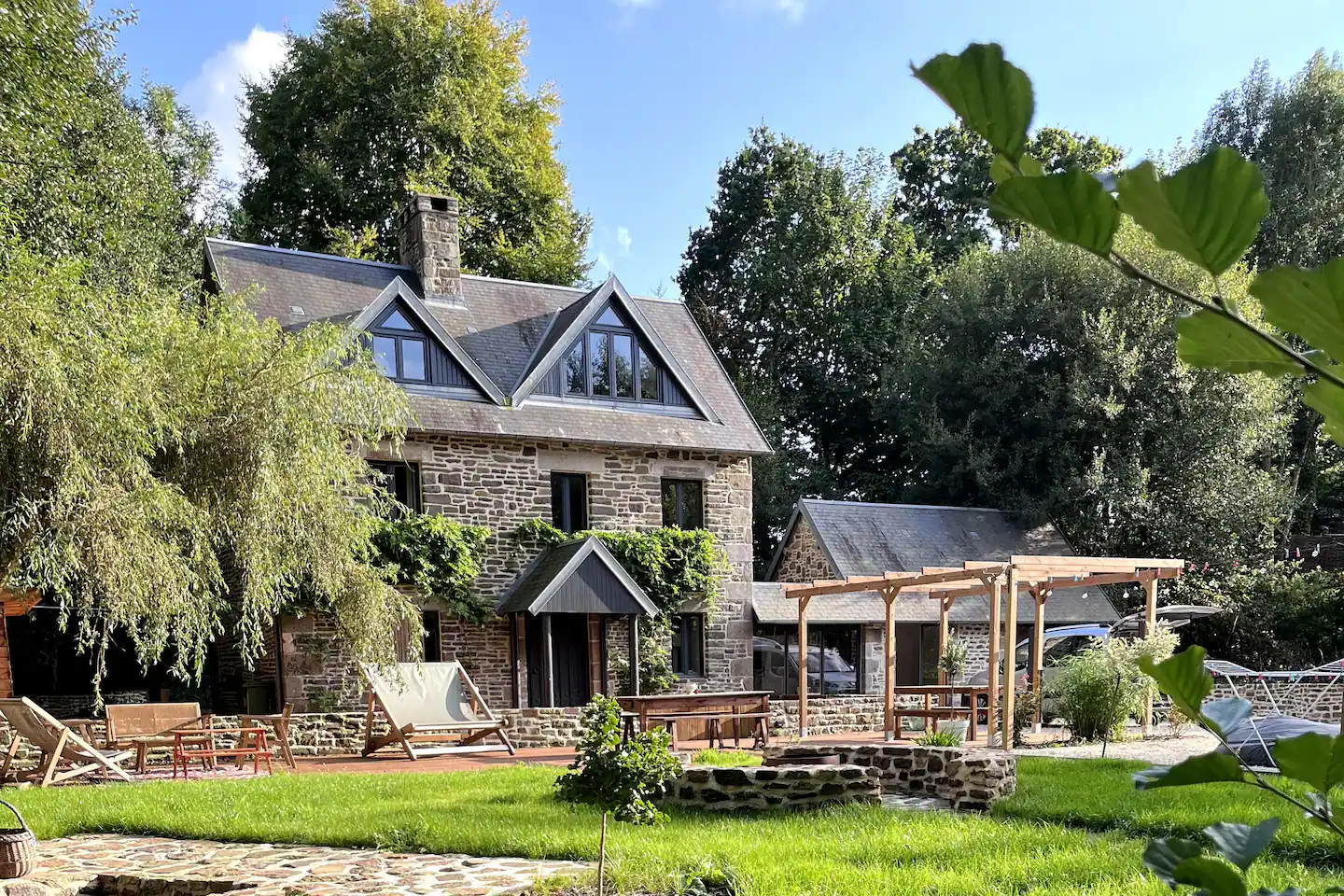Stone house and pergola seen from the sunny lawn