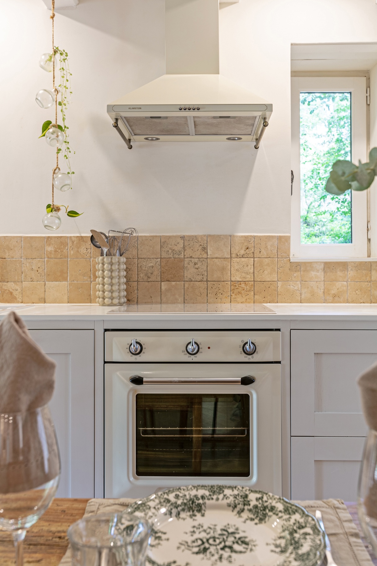 Cream retro oven and hob beneath a window onto the trees