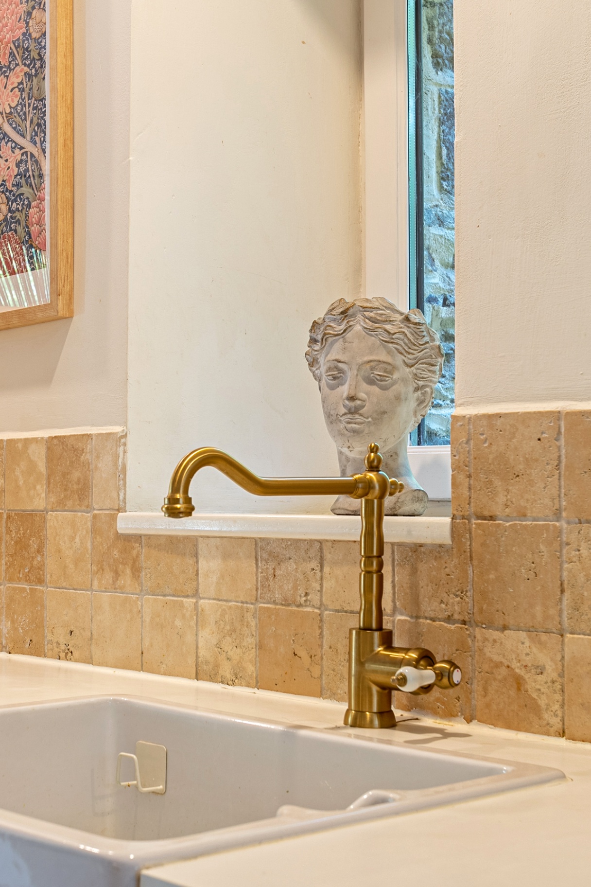 Brass tap and stone bust by the kitchen window