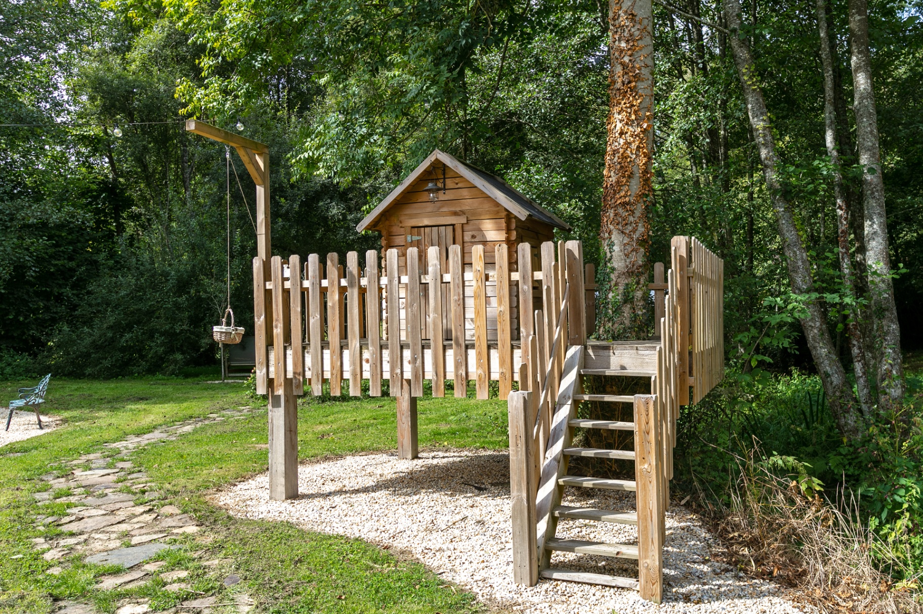 Wooden treehouse on stilts beside a stone path