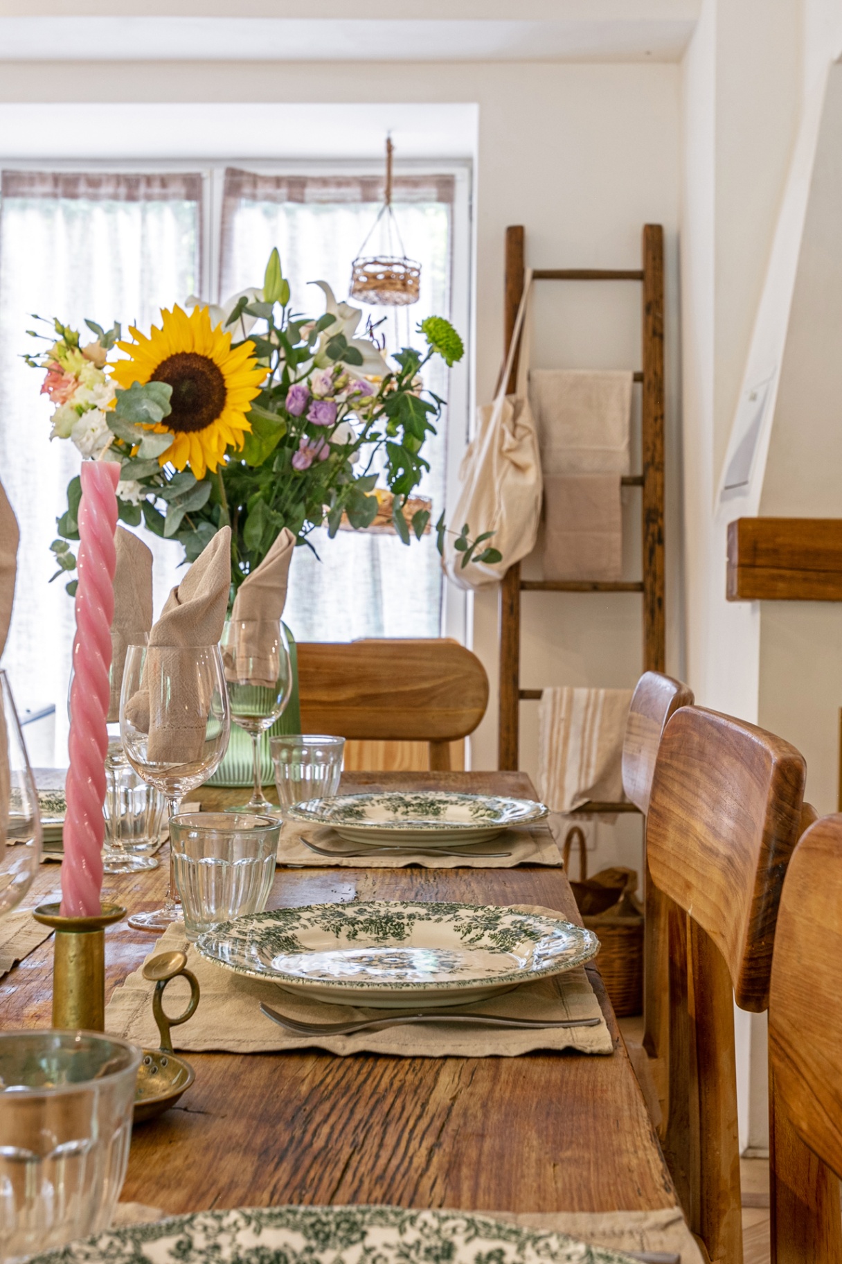 Table laid with green floral plates, sunflowers and a pink candle