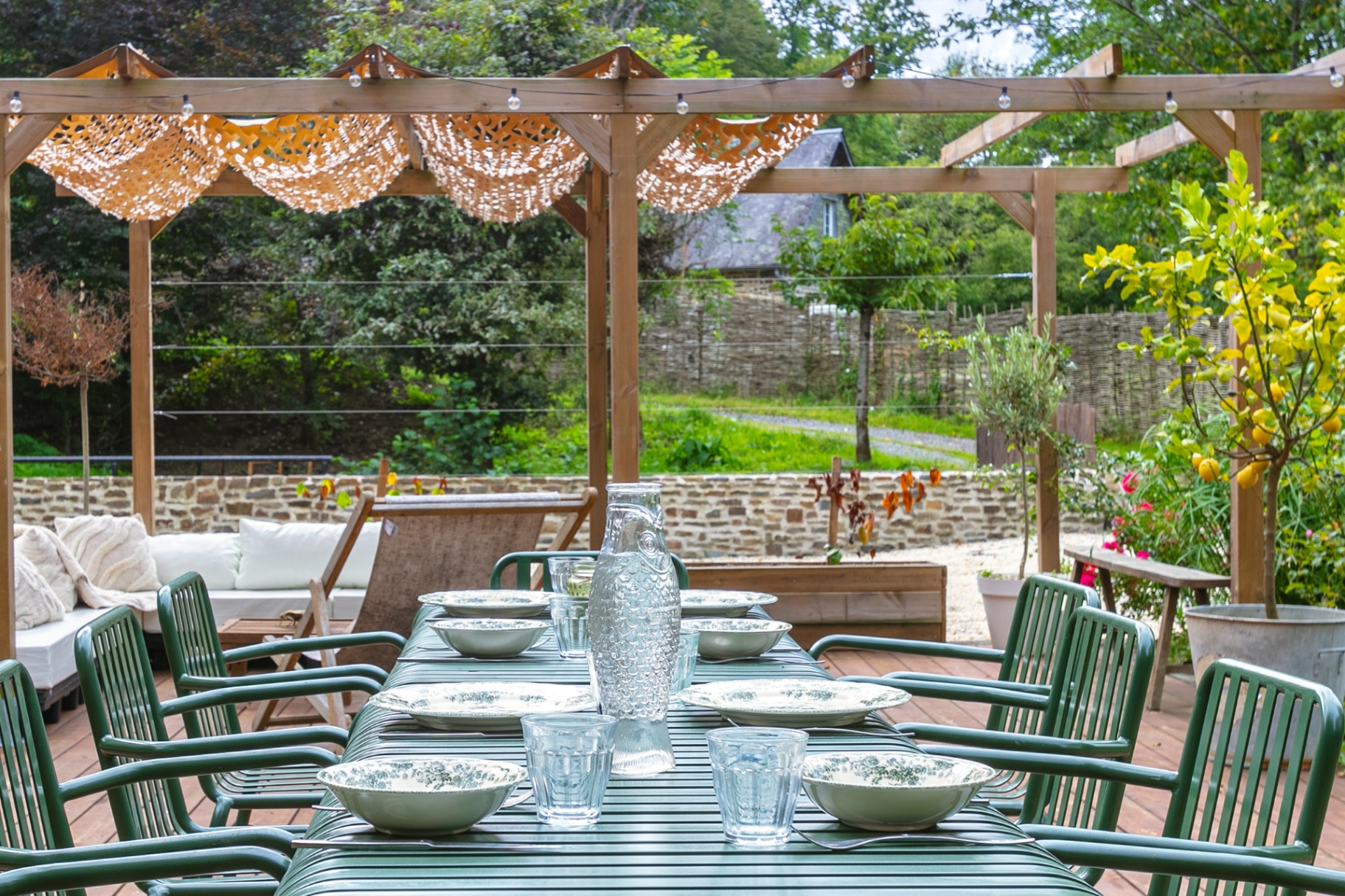 Green outdoor table set for lunch beside a lemon tree