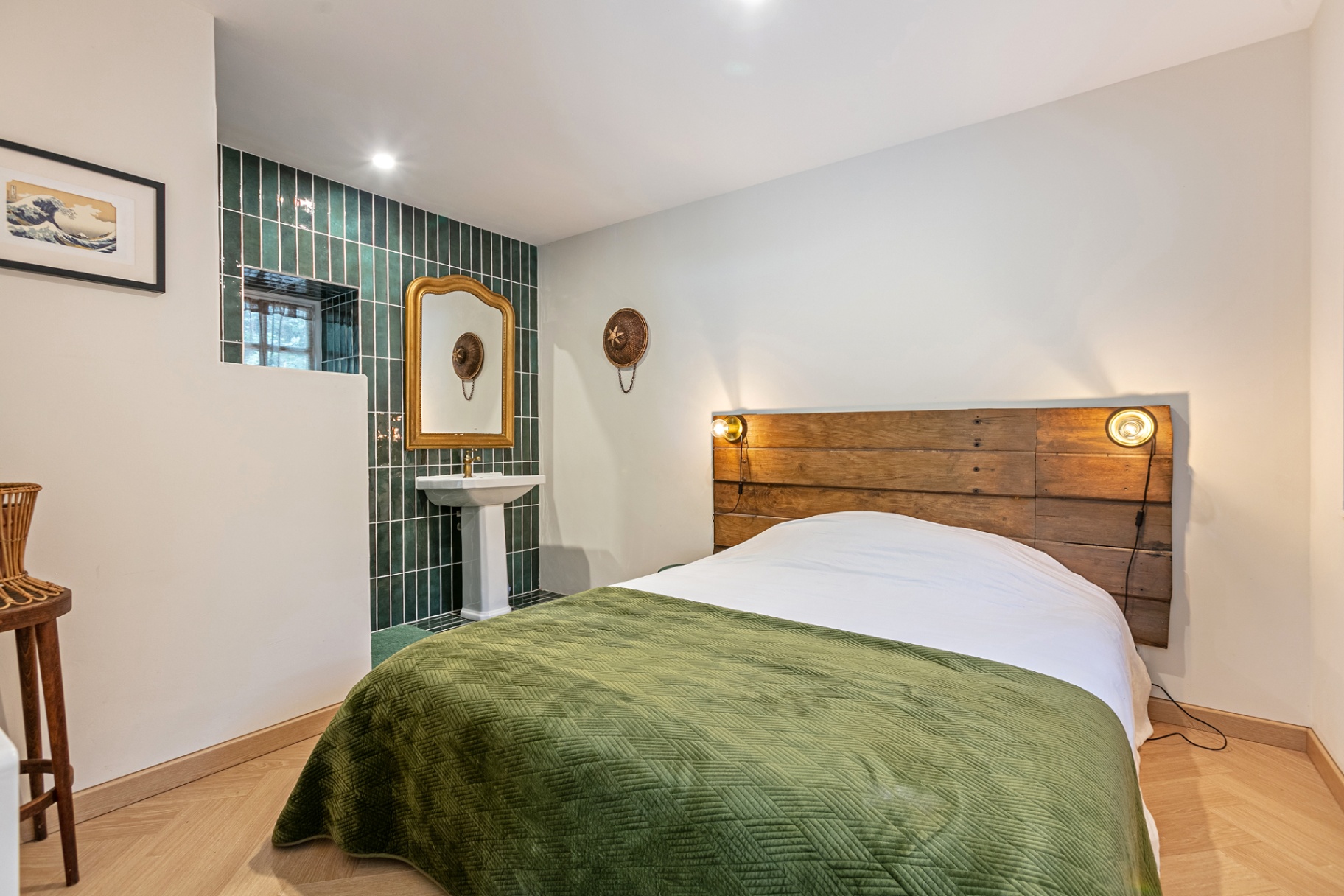 Bedroom with green velvet throw and green-tiled washbasin
