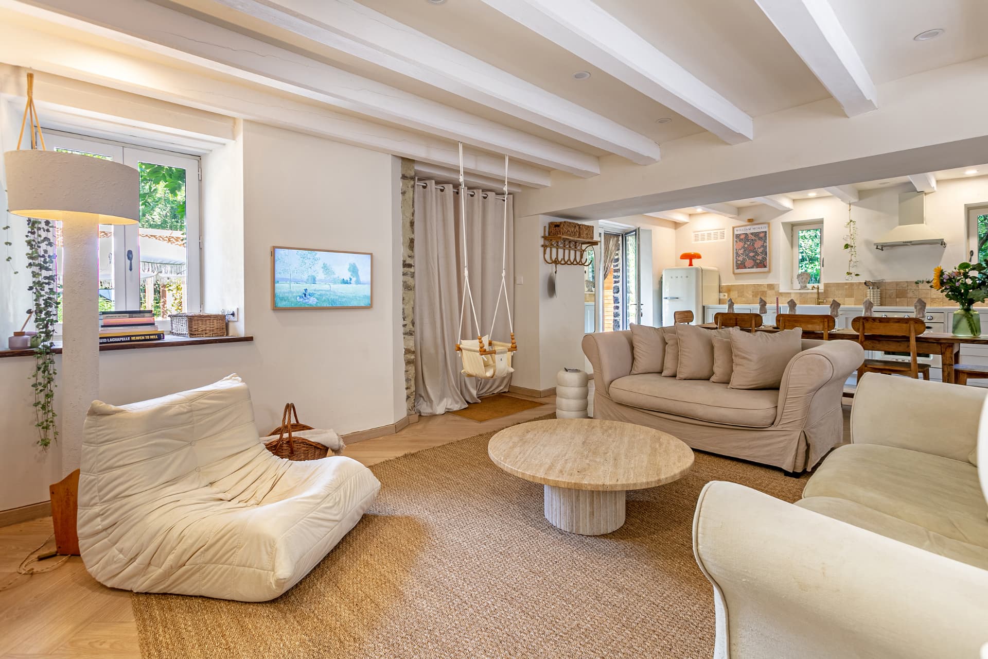 Living room with travertine table, baby swing and open kitchen beyond