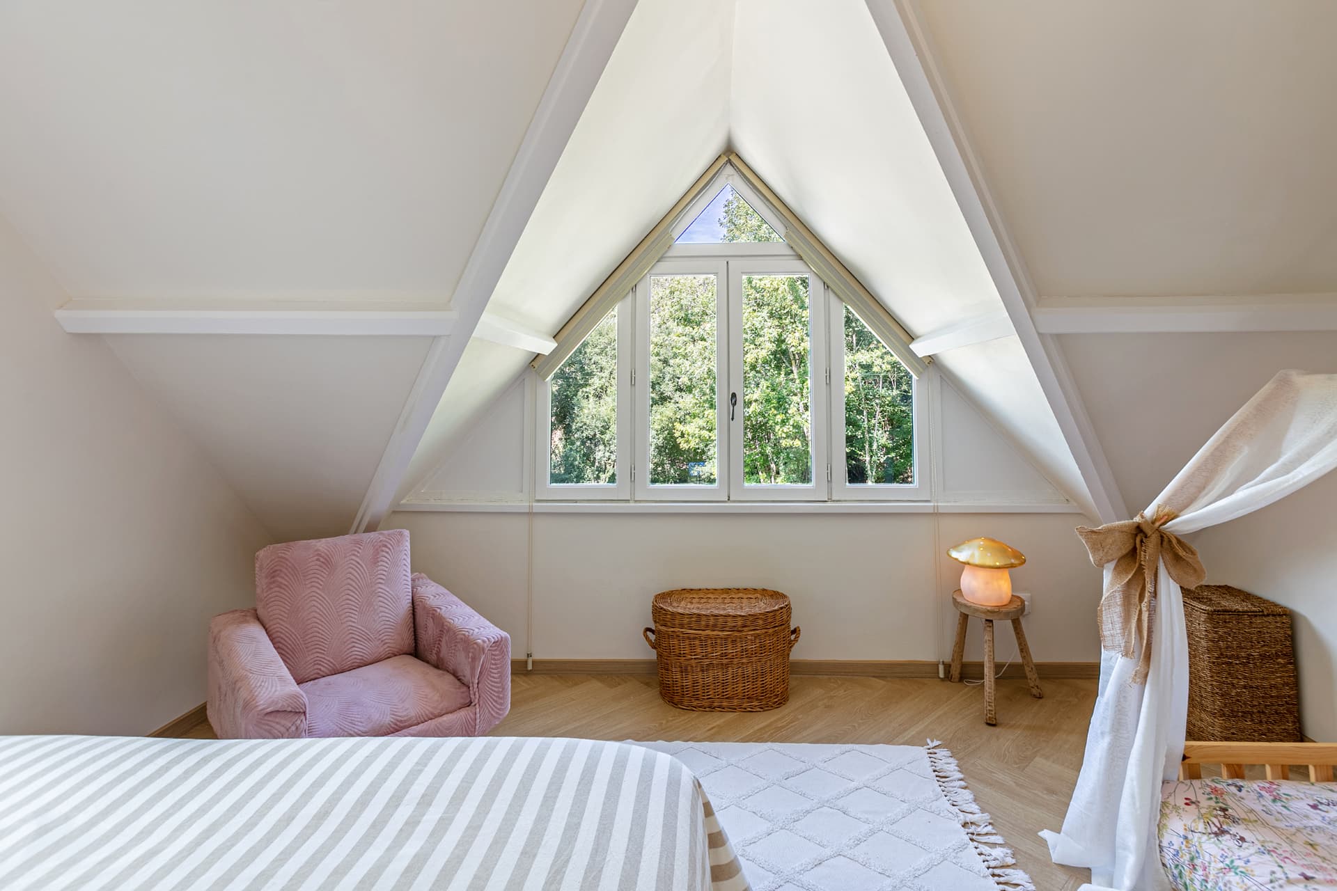 Gable window framing the trees in an attic bedroom