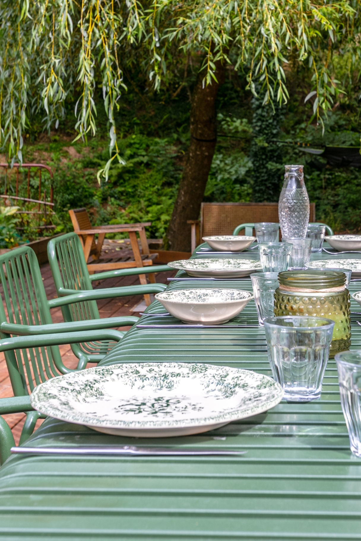 Table laid with green floral plates beneath a willow