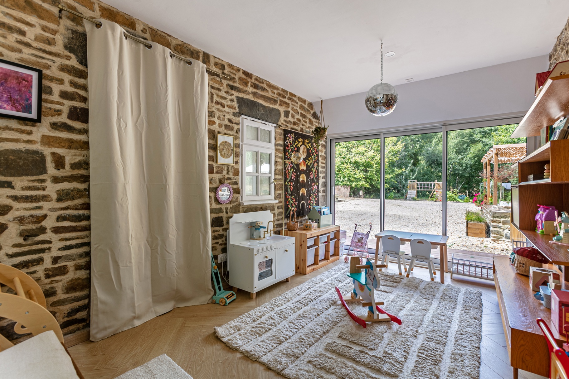 Children's playroom with stone walls and glass doors onto the garden