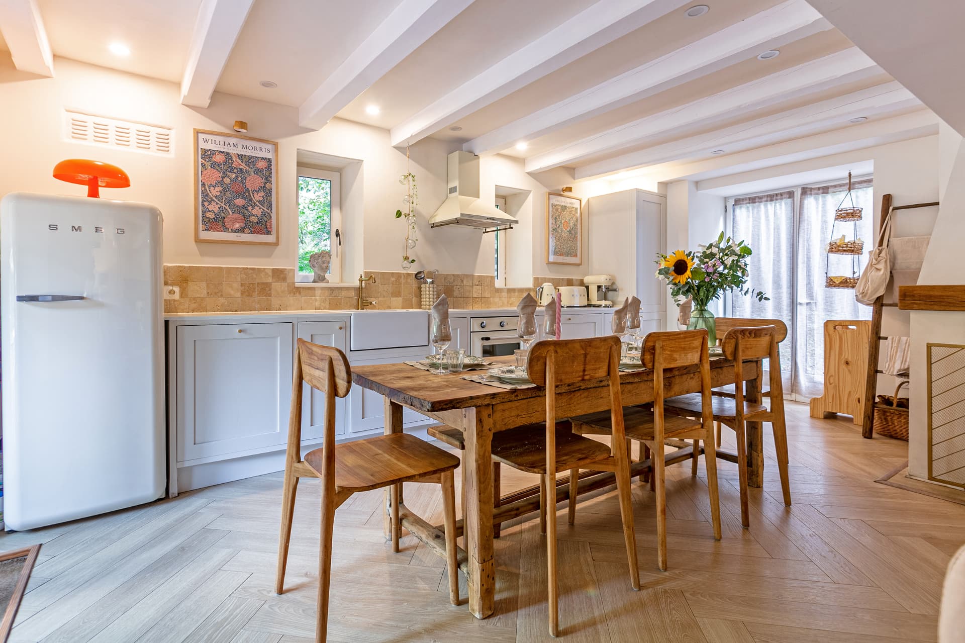 Kitchen and dining table under white beams with garden windows