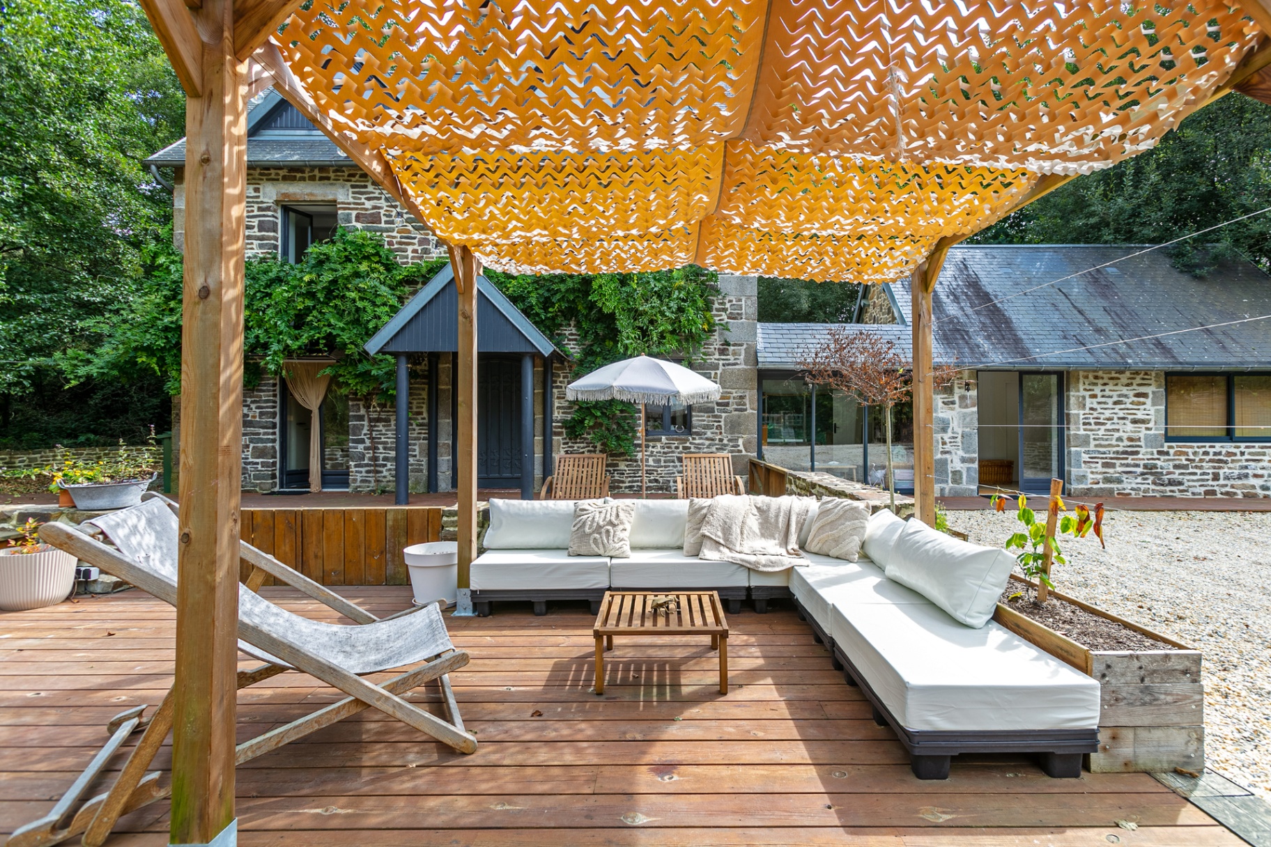 Cream outdoor sofa under the pergola's dappled shade