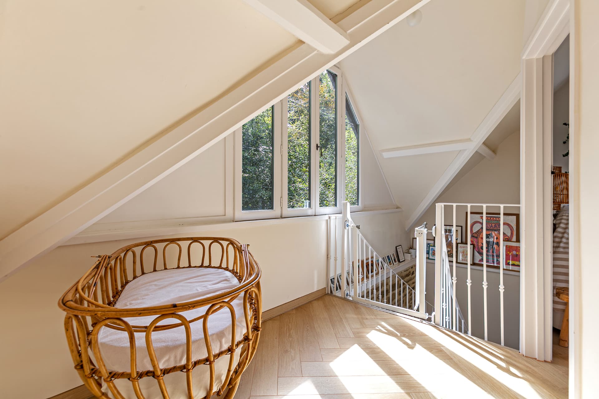 Sunlit landing with rattan cradle and tall windows