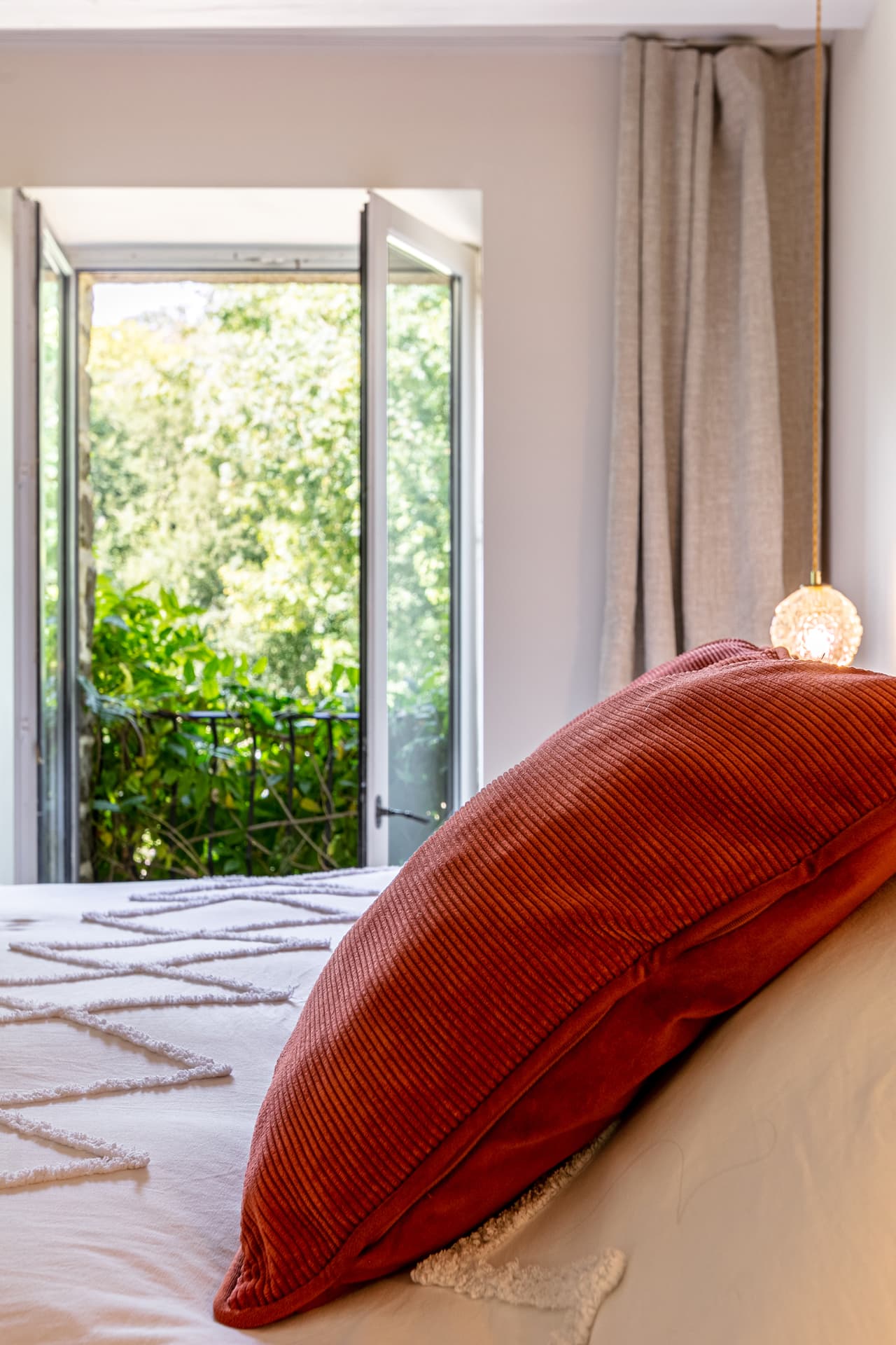 Open balcony window looking onto green foliage