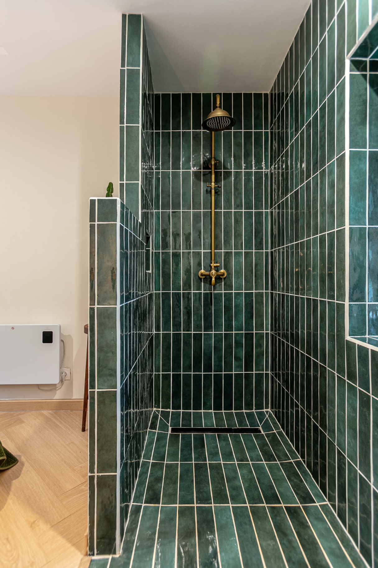 Walk-in shower in deep green tiles with brass rain shower