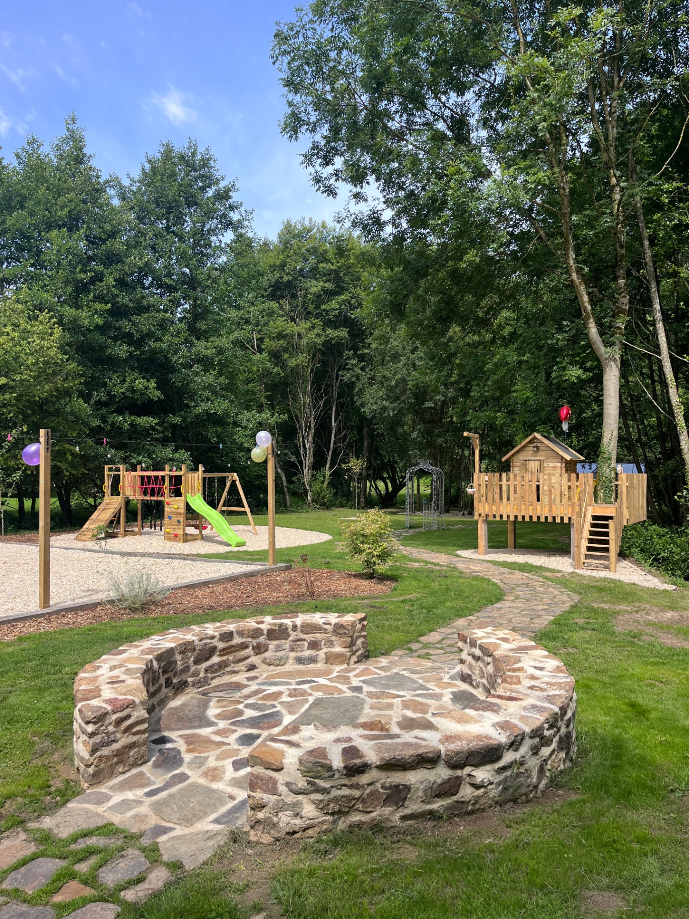Fire pit circle with the play area and treehouse among the trees