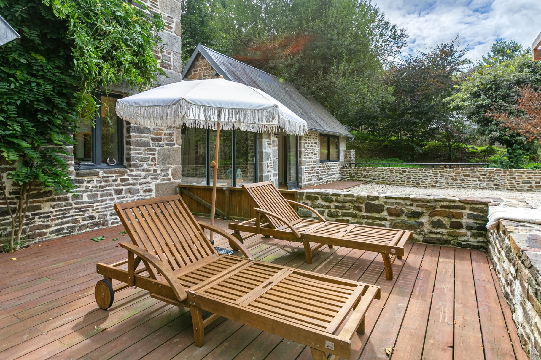 Wooden sun loungers beneath a fringed parasol