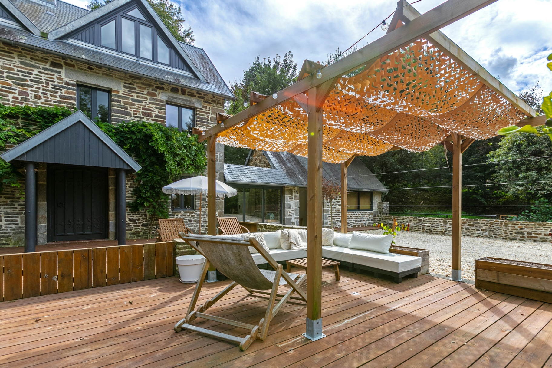 Shaded pergola and deckchair in front of the stone house