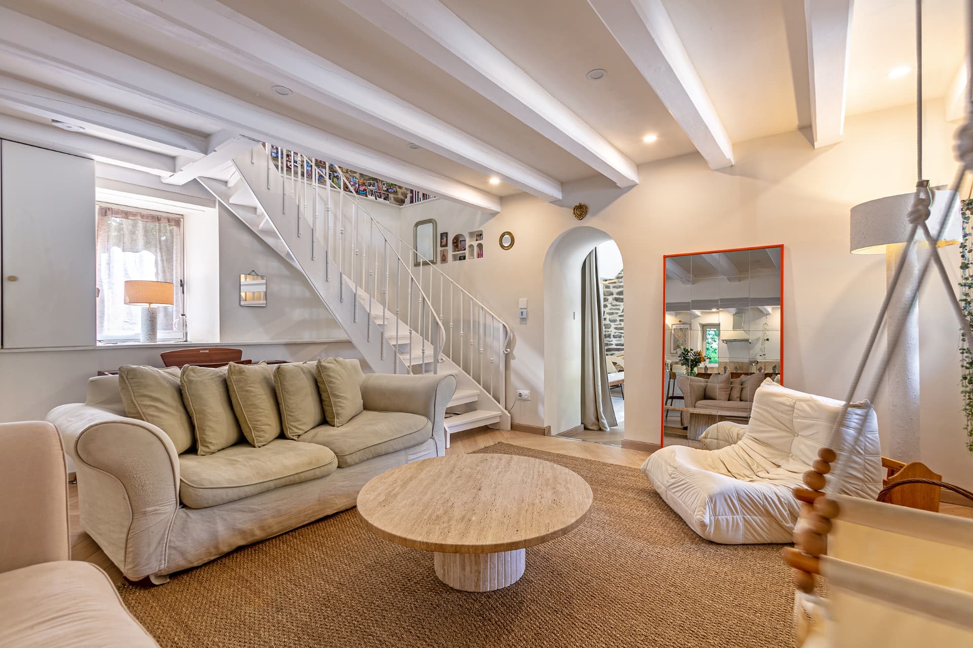Living room with arched doorway, orange mirror and staircase