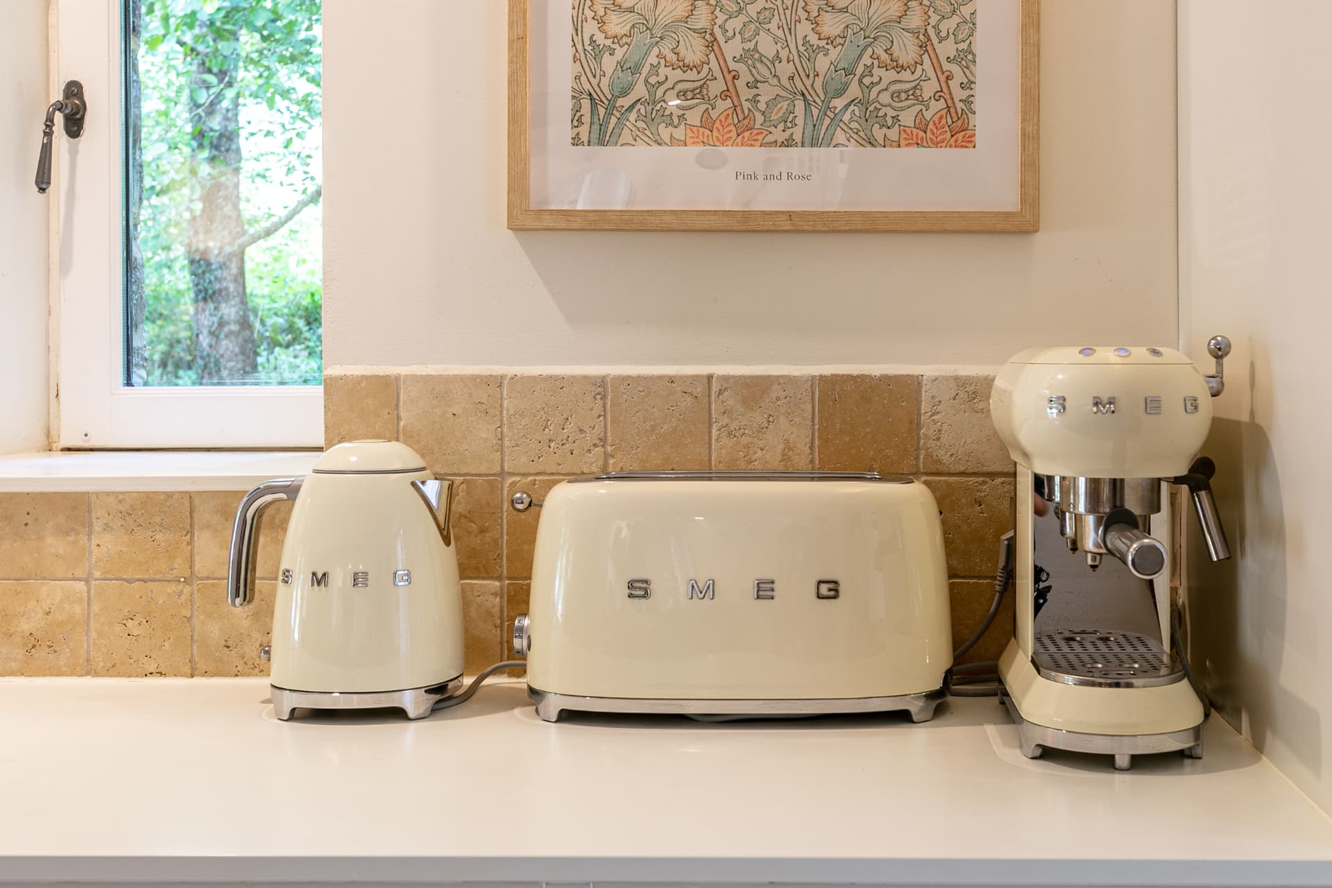 Cream kettle, toaster and espresso machine by a window