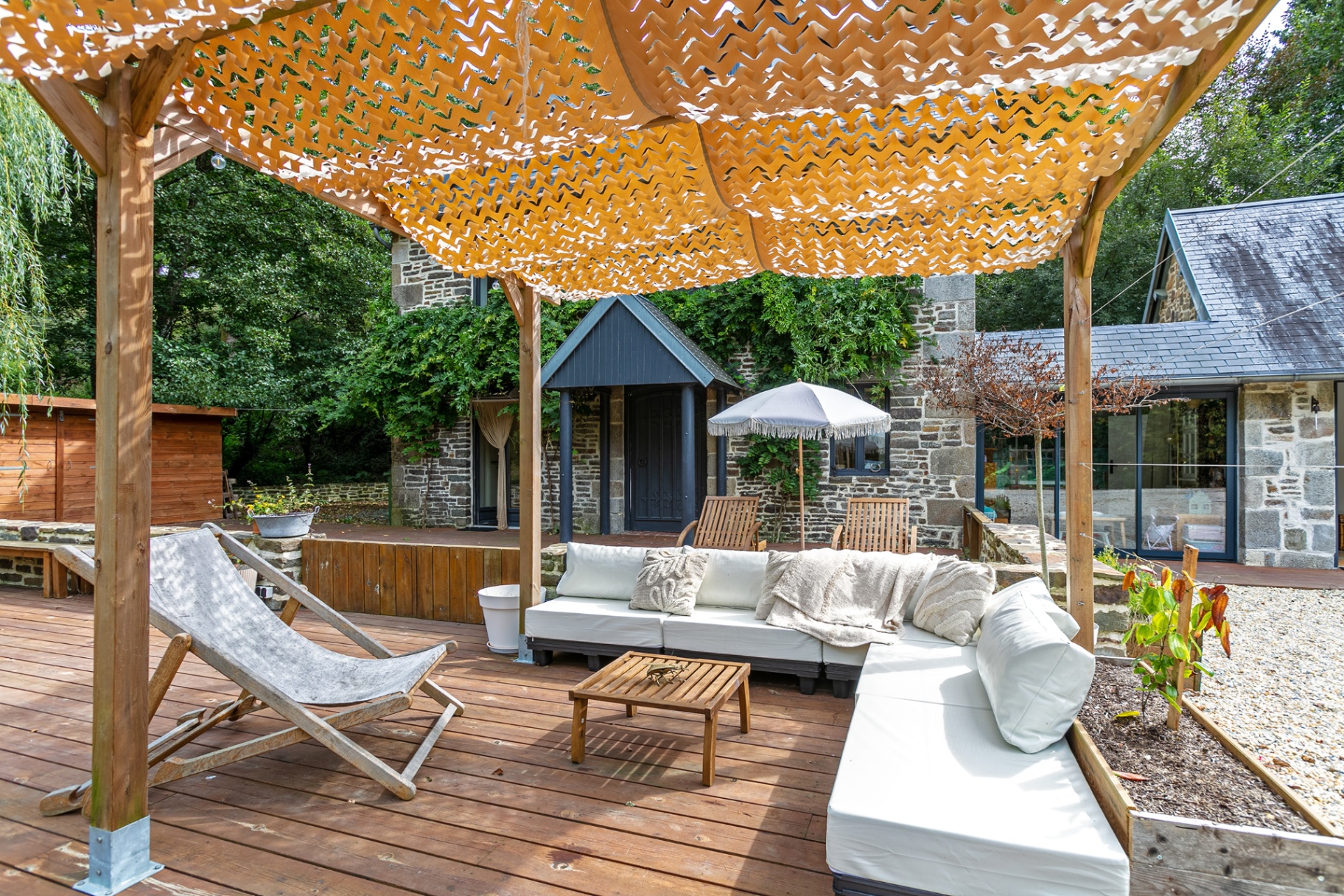 Pergola lounge with wisteria-covered porch behind