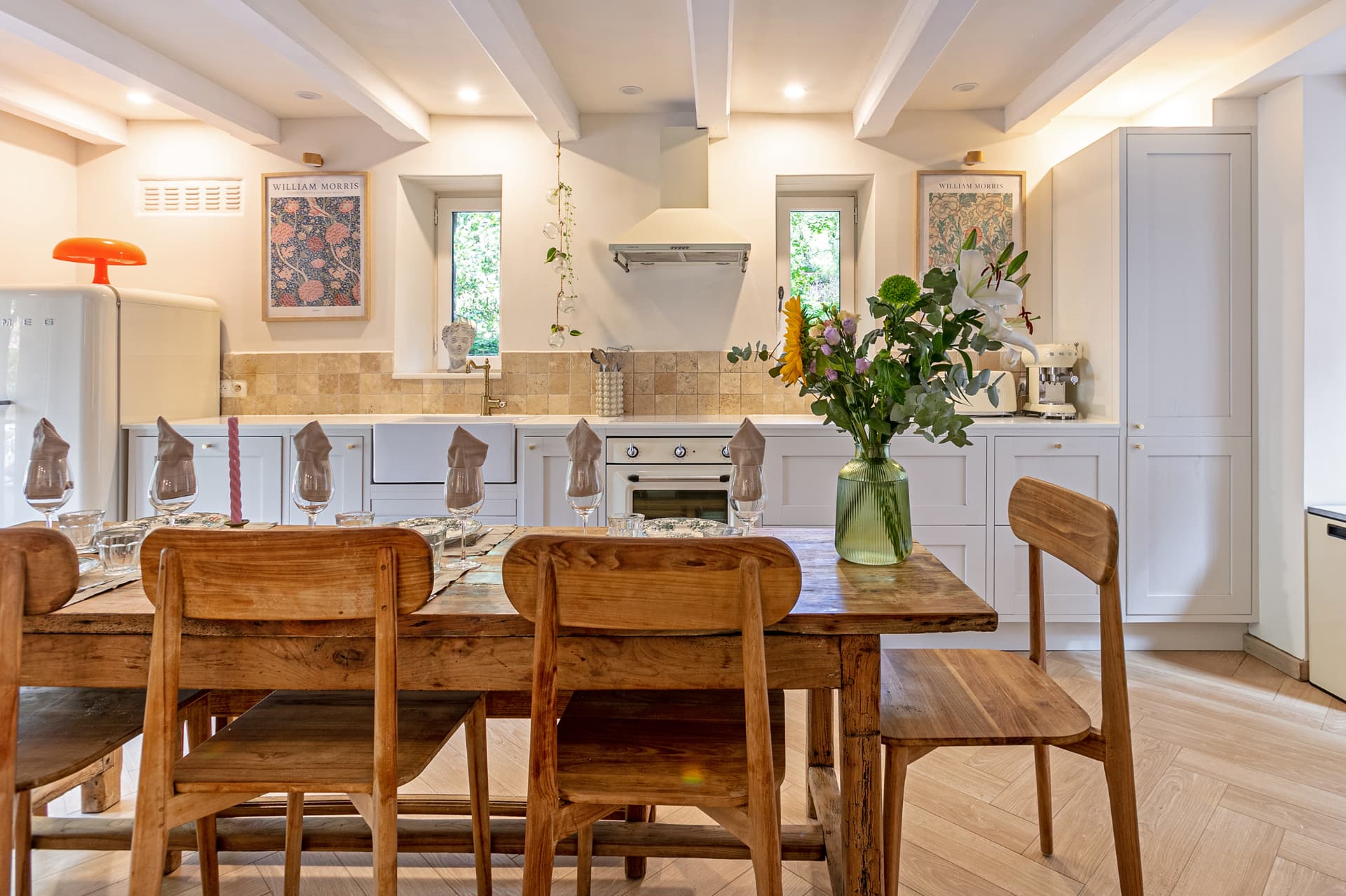 Long farmhouse table set for dinner in front of the kitchen